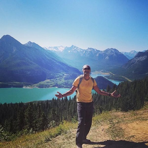 Arms out on a trail above a mountain lake