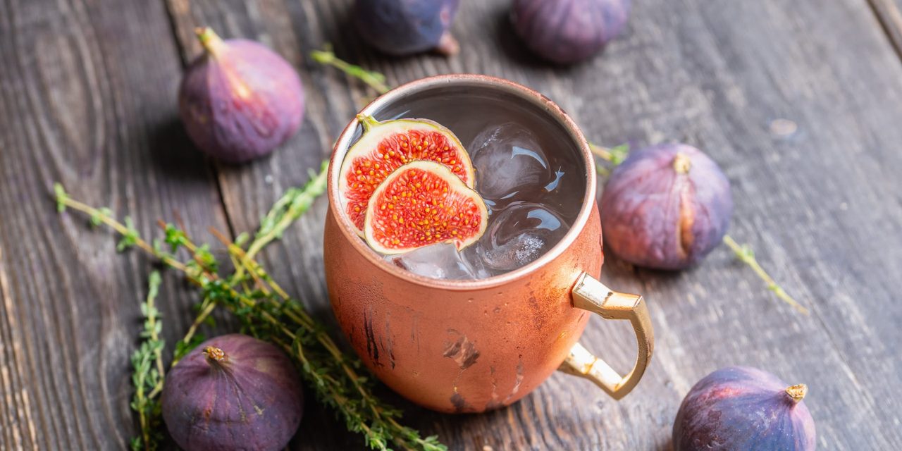 Halved figs in a copper mug on a wooden table