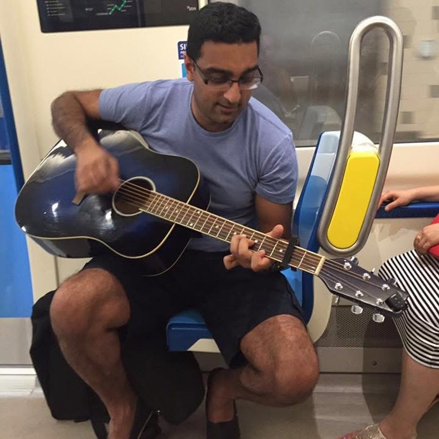 Playing an acoustic guitar on a metro train