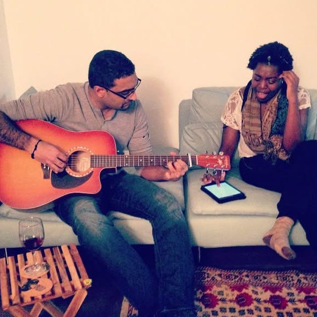 Playing guitar on a couch while a friend sings along